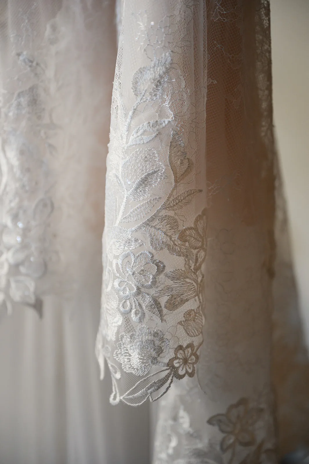 Close-up of white lace fabric with floral embroidery, showing intricate patterns and delicate textures.